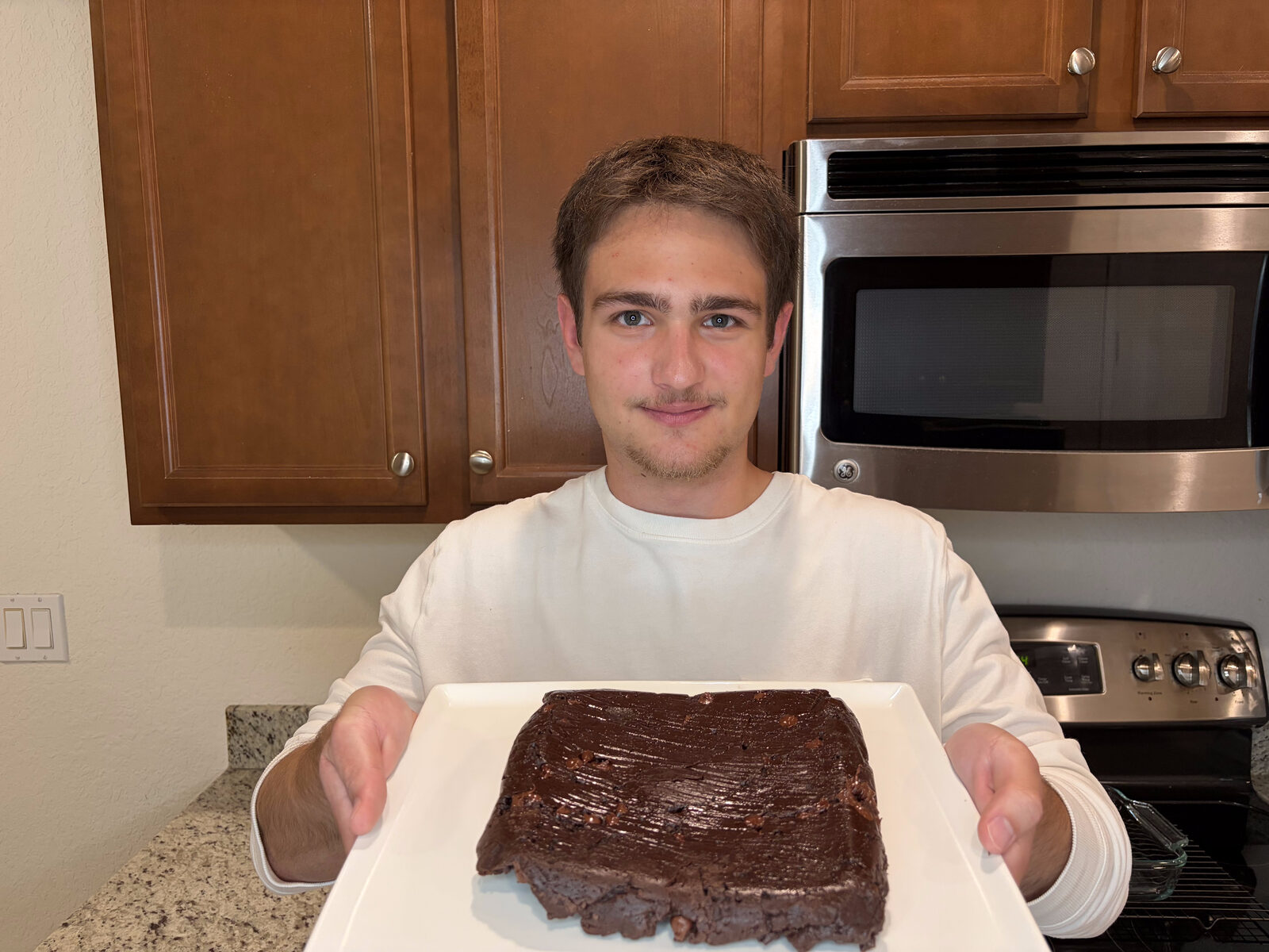 Founder holding a tray with a fresh LifeMaxx protein brownie in the cottage kitchen